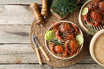 Delicious boiled crabs with lime on wooden table, flat lay. Space for text