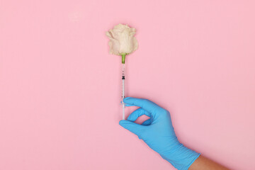 Doctor making injection to rose on pink background, top view
