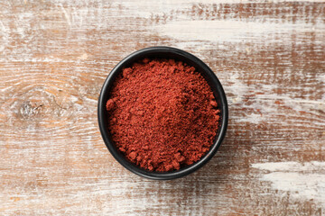 Cranberry powder in bowl on wooden table, top view