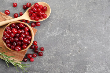 Fresh ripe cranberries and rosemary on grey table, flat lay. Space for text