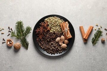 Different spices, nuts and fir branches on light gray textured table, flat lay