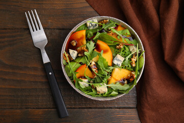 Tasty salad with persimmon, blue cheese and walnuts served on wooden table, top view