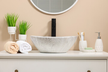 Different bath accessories and personal care products near sink on bathroom vanity