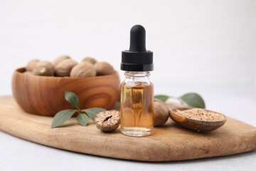 Nutmeg essential oil, nuts and leaves on light table