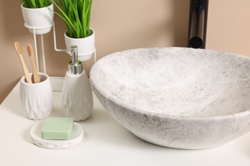 Different bath accessories and personal care products near sink on bathroom vanity