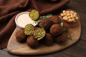 Delicious falafel balls, chickpeas and sauce on wooden table