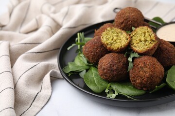 Delicious falafel balls, herbs and sauce on white table, closeup