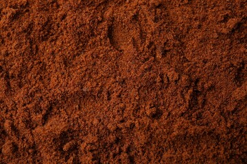 Heap of nutmeg powder as background, top view