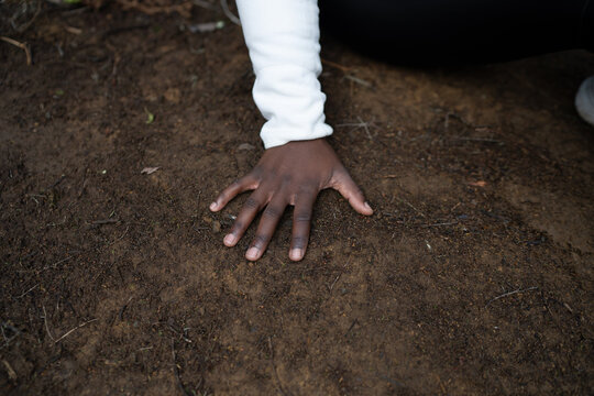 Unrecognizable black woman touching wet ground with hand