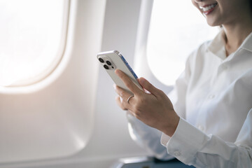 young woman hand using modern smartphone in airplane, businessman typing message during flight, business trip, people working in airplane on mobile phone.