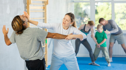 Woman and man in group self-defense classes practicing sparring technique of blowing to chin in gym