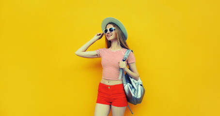 Beautiful young woman posing in summer straw hat, red shorts with backpack