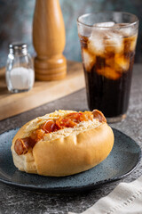 Homemade hot dog with grilled sausage, tomato sauce and straw potatoes.