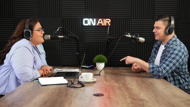 Hispanic talk show host and guest having a fun interview and conversation while recording in a studio