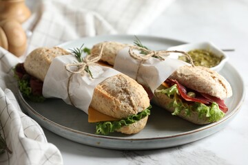 Delicious sandwiches with bresaola, lettuce and cheese on white marble table, closeup