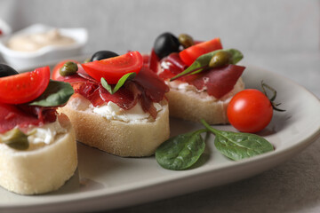 Delicious sandwiches with bresaola, cream cheese, olives and tomato on table, closeup