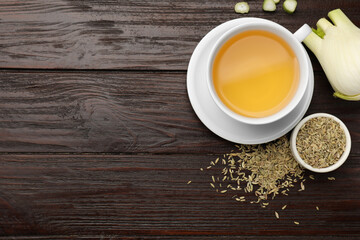 Fototapeta na wymiar Fennel tea in cup, seeds and fresh vegetable on wooden table, flat lay. Space for text