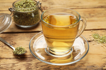 Aromatic fennel tea and seeds on wooden table, closeup