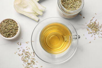 Aromatic fennel tea, seeds and fresh vegetable on white table, flat lay