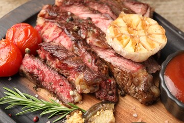 Delicious grilled beef steak with vegetables and spices on table, closeup