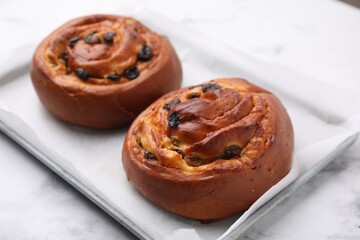 Delicious rolls with raisins on white table, closeup. Sweet buns