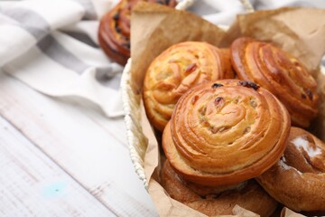 Delicious rolls with raisins on white wooden table, closeup and space for text. Sweet buns