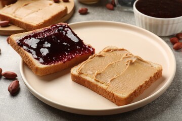 Tasty peanut butter sandwiches with jam on gray table, closeup