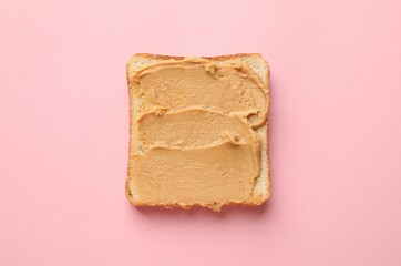 Tasty peanut butter sandwich on pink background, top view