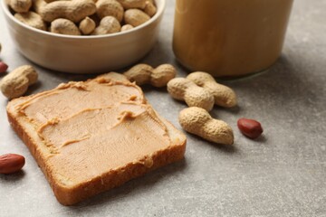 Tasty peanut butter sandwich and peanuts on gray table, closeup