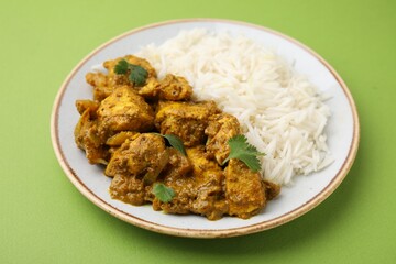 Delicious chicken curry with rice on green background, closeup