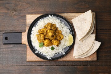 Delicious chicken curry with rice and tortillas on wooden table, top view