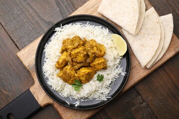 Delicious chicken curry with rice and tortillas on wooden table, top view