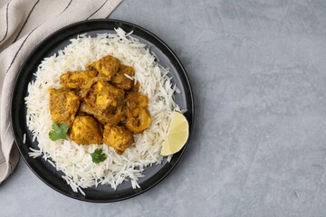 Delicious chicken curry with rice on grey table, top view. Space for text
