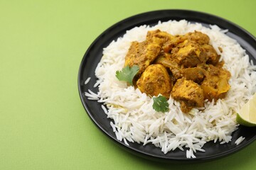 Delicious chicken curry with rice on green background, closeup