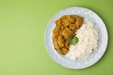 Delicious chicken curry with rice on green background, top view. Space for text