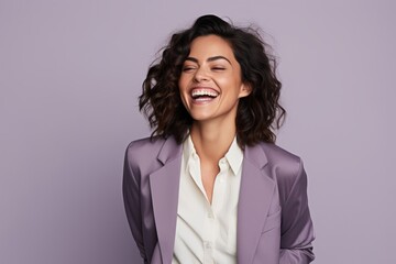 Happy businesswoman laughing. Beautiful young woman smiling and looking at camera while standing against purple background