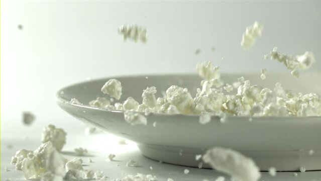 Fresh cottage cheese falls into the plate. Filmed on a high-speed camera at 1000 fps. High quality FullHD footage