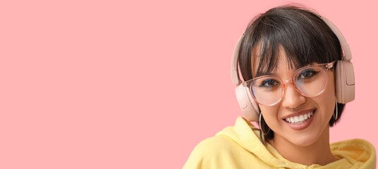 Stylish woman with nose piercing and headphones on pink background with space for text