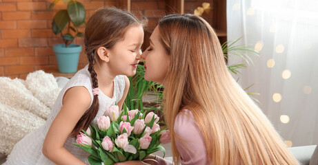 Naklejka premium Cute little girl greeting her mother with tulips at home