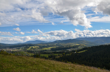 Picturesque view with high mountains covered with forests, meadows and houses scattered across the landscape, fitting well into the natural environment. Carpathians, Ukraine