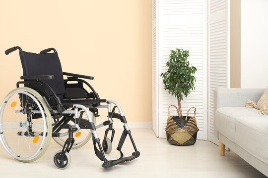 Empty wheelchair with folding screen, plant and sofa in living room