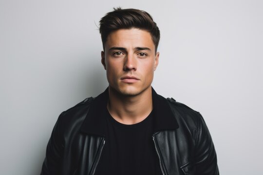 Handsome young man in a black leather jacket on a gray background.
