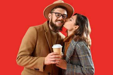 Happy couple in love with cups of coffee on red background