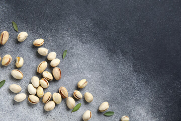Tasty pistachio nuts and leaves on grunge background