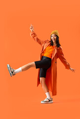 Fototapeta na wymiar Stylish young Asian woman on orange background