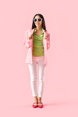 Stylish young Asian woman on pink background