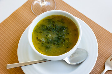 Bowl of flavorful Caldo Verde soup, traditional soup made with potatoes, chourico sausage and thinly sliced collard greens or kale, Portuguese cuisine