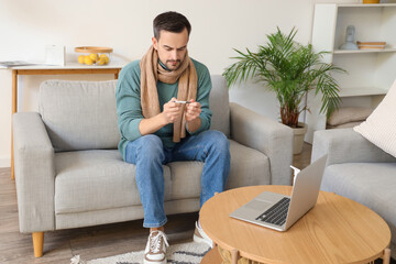 Ill young man with thermometer video chatting at home