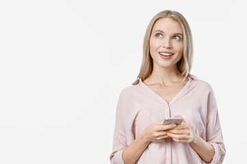 Attractive thinking young blonde woman posing isolated over white background using mobile phone. Pensive lady freelancer looking at copyspace with cellphone