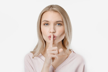 Portrait of attractive girl with finger on lips isolated over white background. Top secret, silent gesture. Woman with emotion looking at camera